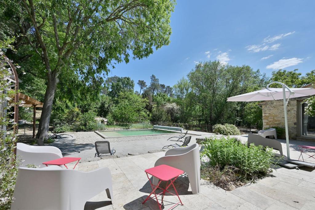 a patio with chairs and an umbrella and a pool at Mas Arguin - Charmante maison avec piscine in Barjac