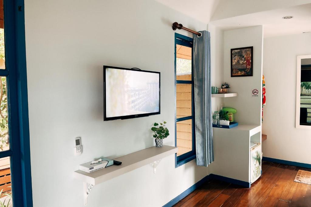a living room with a tv on a wall at Cruiser Island By Swiss-Belhotel in Ko Lone
