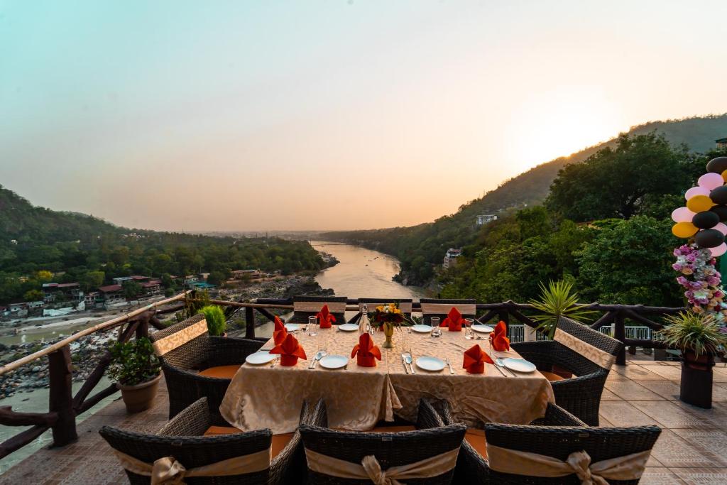 a table on a balcony with a view of a river at Divine Resort & Spa in Rishīkesh