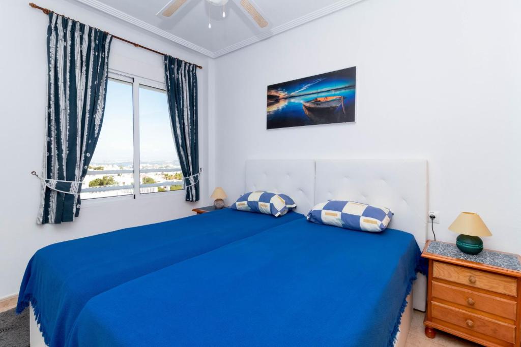 a bedroom with a blue bed and a window at San Sebastián 22 in Torrevieja