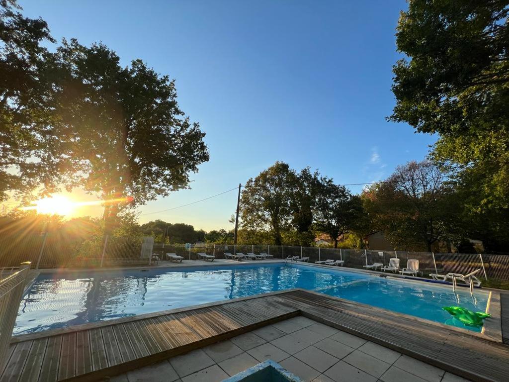 a swimming pool with the sun setting in the background at Emplacement tente camping car in Saint-Aubin-de-Nabirat