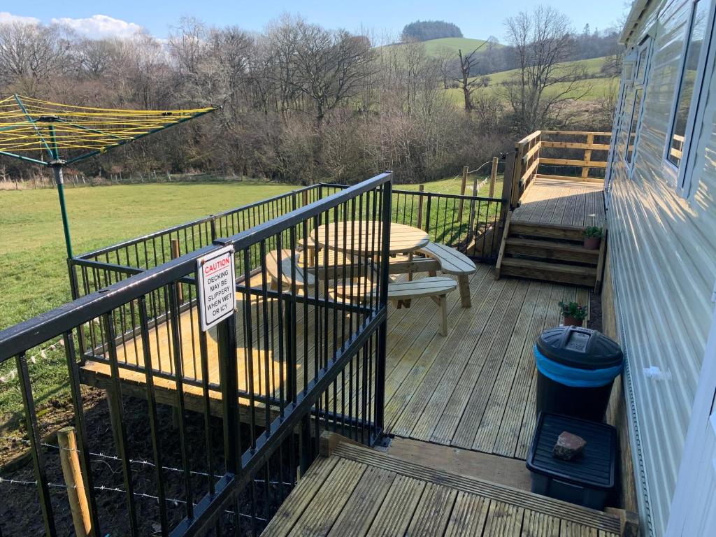a wooden deck with a table and an umbrella at Farm stay caravan on working farm in Dacre