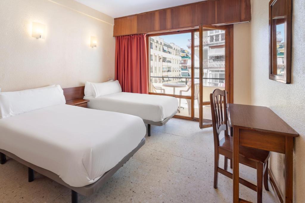 a room with two beds and a desk and a window at Hotel Andalucía in Benidorm