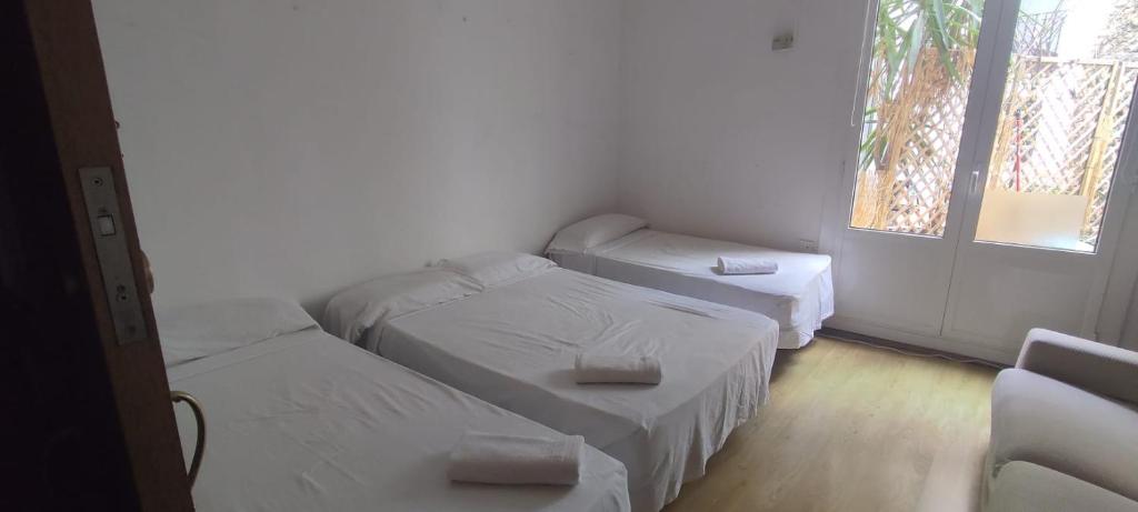 a room with three beds and a window at Alojamiento Compartido En Rambla De Cataluña in Barcelona