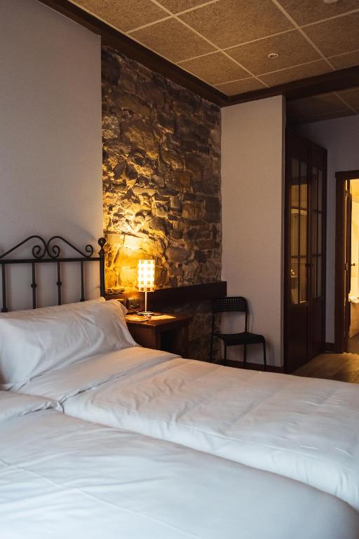 a bedroom with two beds and a stone wall at San Sebastián DOT Rooms in San Sebastián