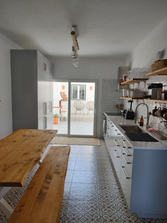 eine Küche mit weißen Schränken und einem Holztisch in der Unterkunft Casa da Paz #1 in Vila Nova de Milfontes