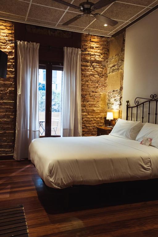 a bedroom with a large bed and a brick wall at San Sebastián DOT Rooms in San Sebastián