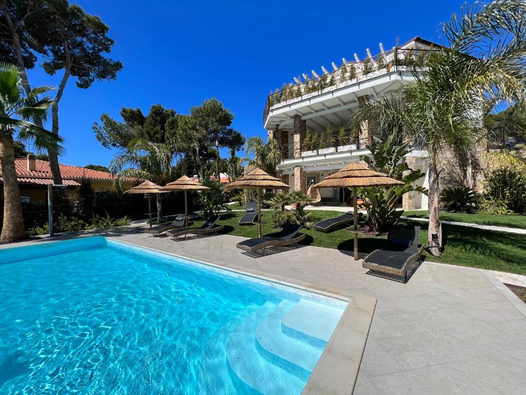 a pool in front of a building with umbrellas at Suite Villa Domos in Porto Pino