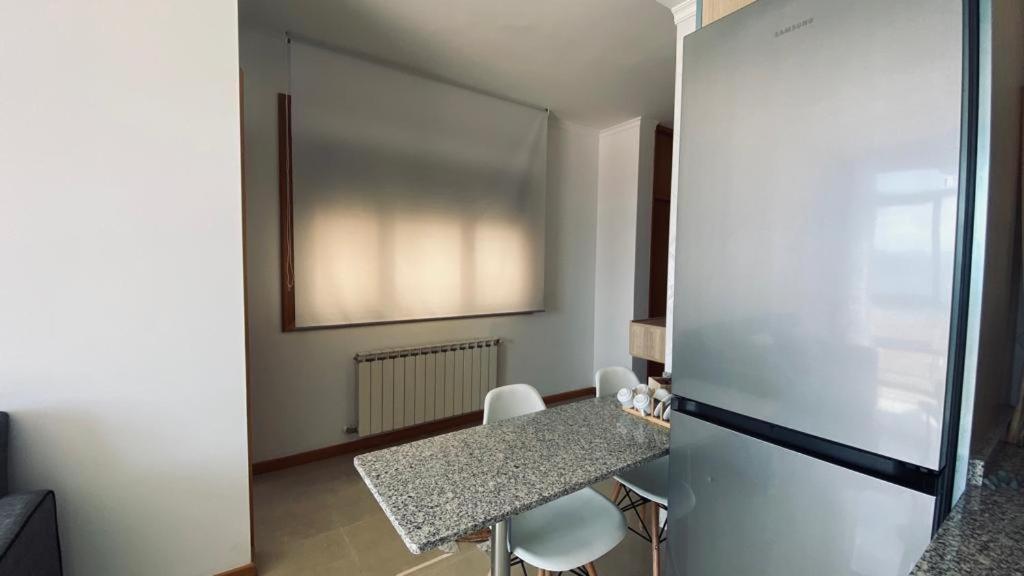 een keuken met een tafel, stoelen en een koelkast bij Alojamiento Fragata Lealtad in Moaña