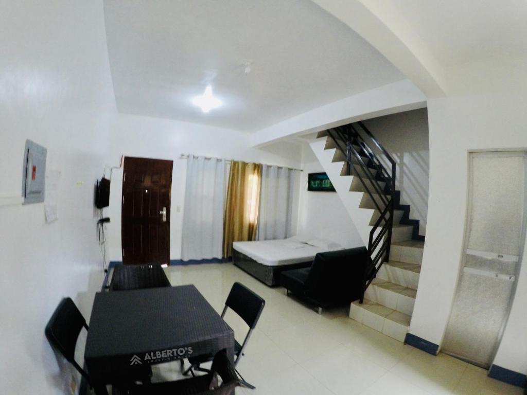 a room with a staircase and a table and chairs at Alberto's Lodging House in Mariveles
