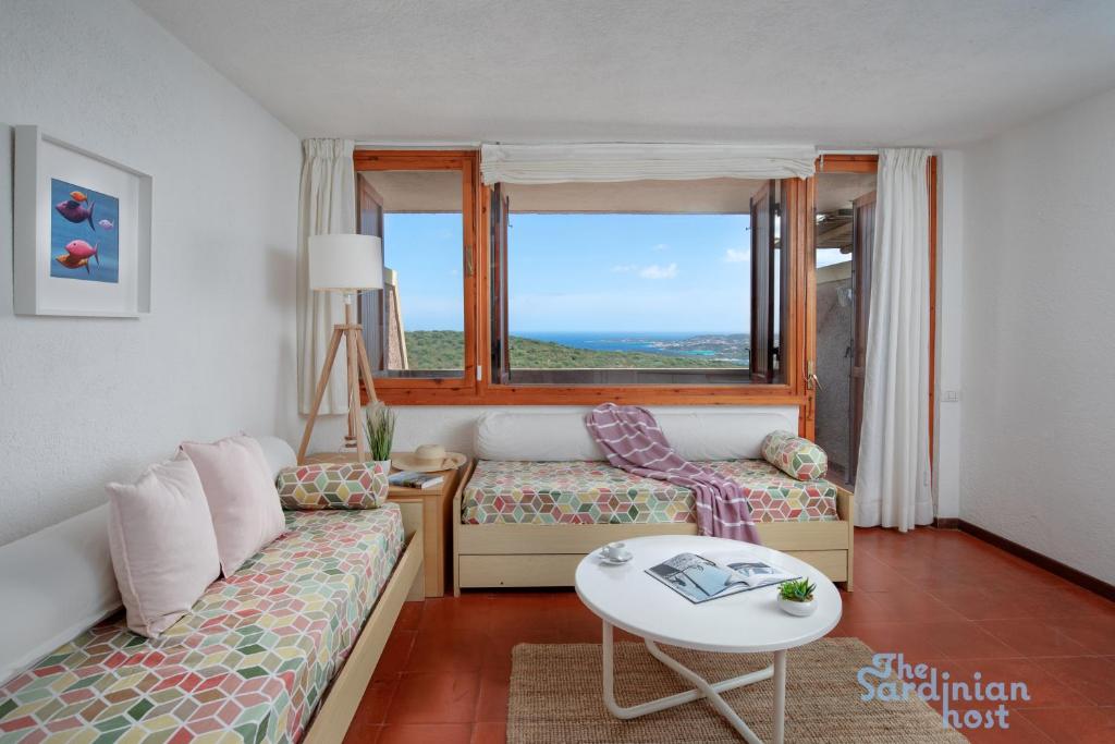 a living room with a couch and a table and a window at Iole's House, finestra sul mare in Olbia