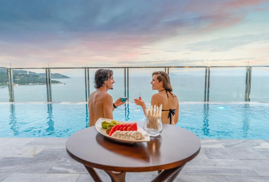 a man and woman standing next to a table with a plate of food at Grand Gold Hotel in Da Nang