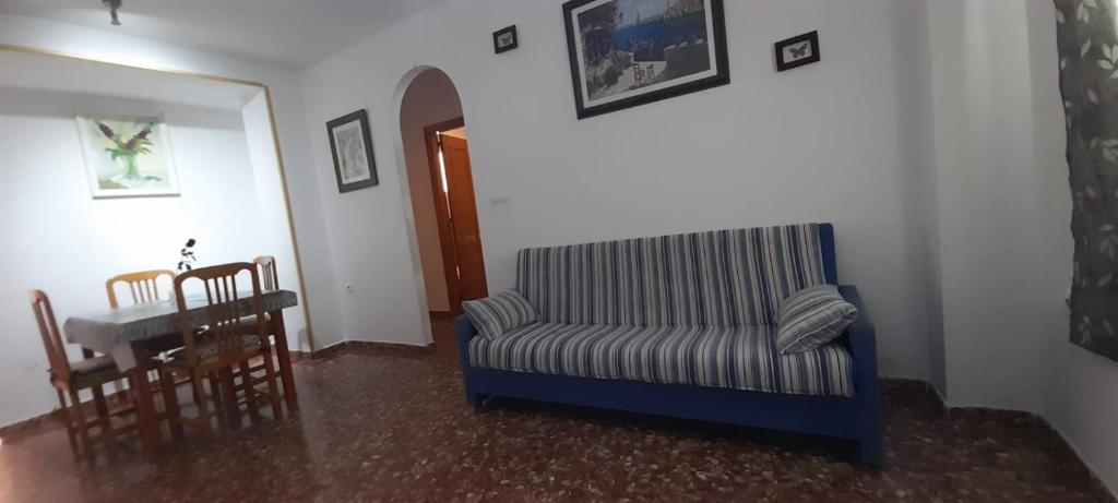 ein Wohnzimmer mit einem blauen Sofa und einem Tisch in der Unterkunft APARTAMENTO GRETA in Torrenueva