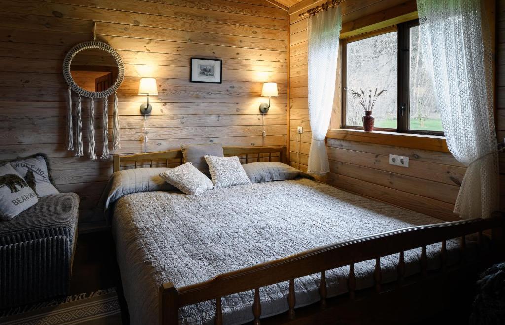 a bedroom with a bed in a wooden room at Atokvėpis in Vydmantai