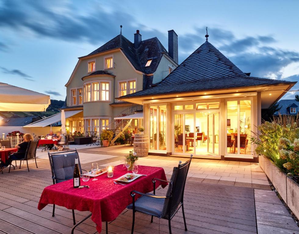 eine Terrasse mit einem Tisch und Stühlen sowie ein Haus in der Unterkunft Gästehaus & Weingut Clüsserath-Weiler in Trittenheim