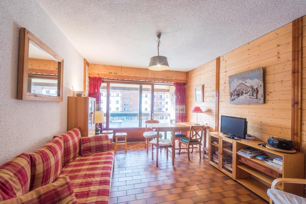 ein Wohnzimmer mit einem Sofa und einem Tisch mit einem TV in der Unterkunft Serre-chevalier Vallée - Briançon in Briançon