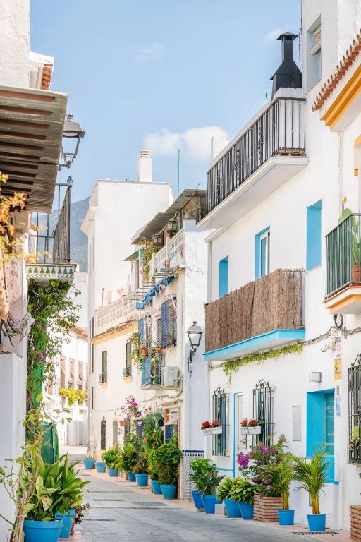 a street in positano with white houses and potted plants at Bella Marbella in Marbella