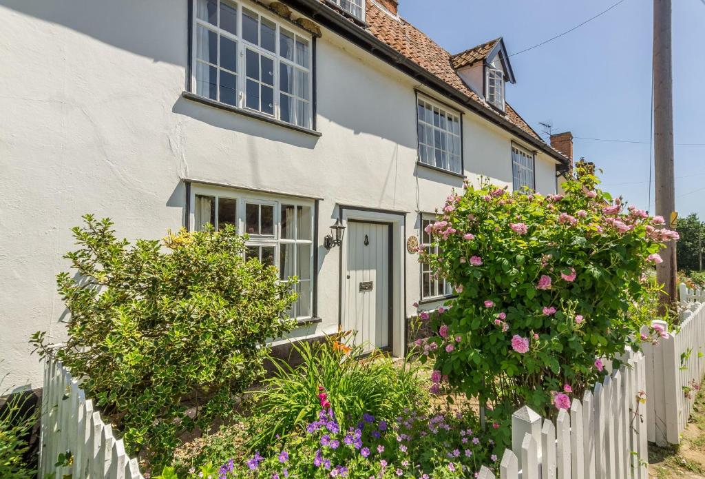 a white house with a white fence and flowers at Holly Cottage in Huntingfield