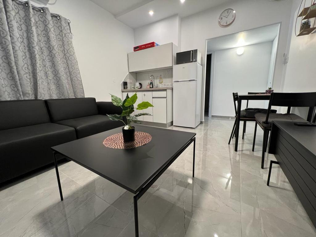 ein Wohnzimmer mit einem schwarzen Sofa und einem Tisch in der Unterkunft דירת 2 חדרים in Bat Yam