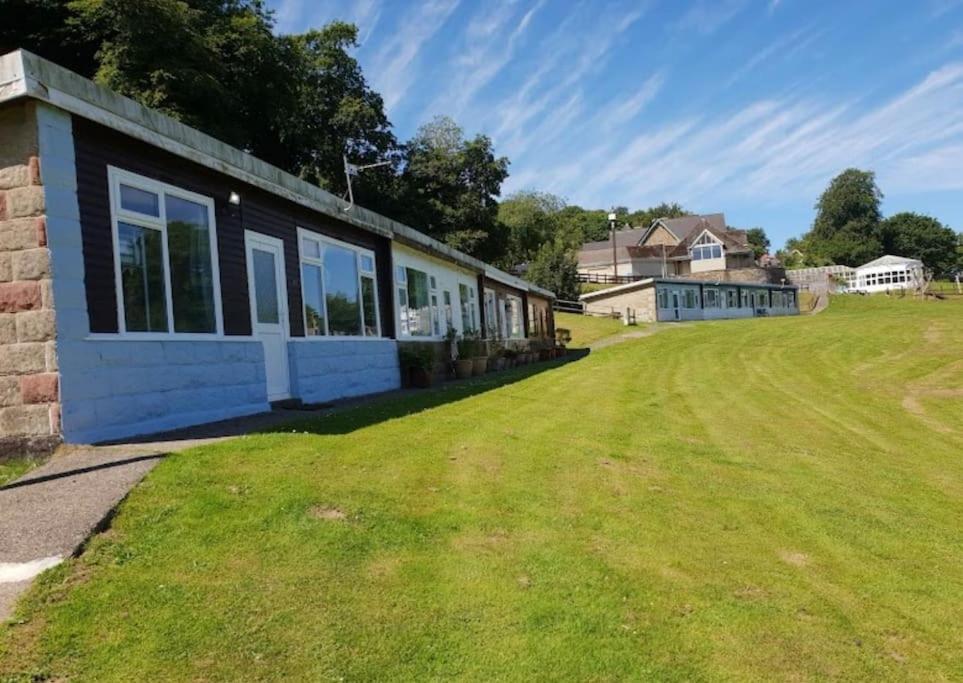 a house on a grassy field next to a building at Sea Valley 33 Bideford Bay Holiday Park in Bideford