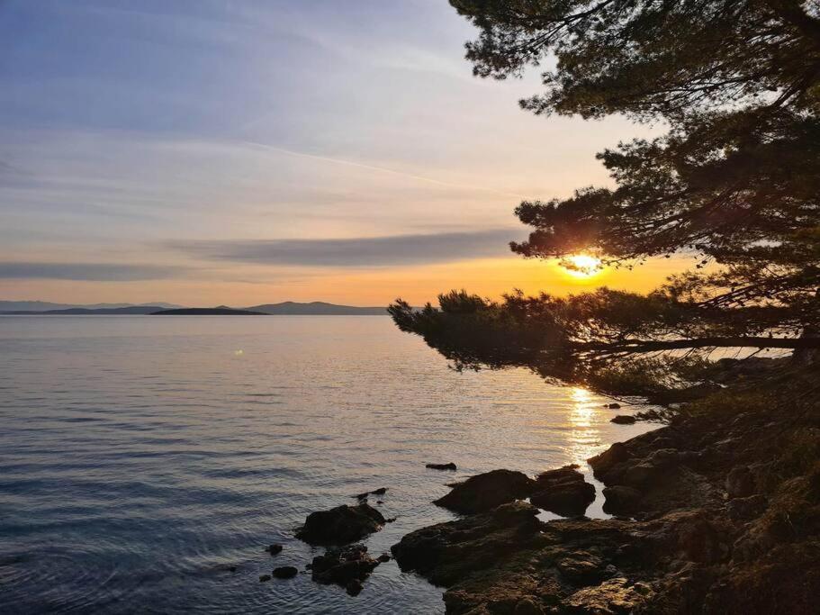 a sunset on the shore of a body of water at Apartment Zaglav 3 - first sea row in Zaglav