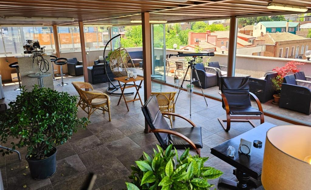 a patio with chairs and tables on a roof at Hotel Genio in Tbilisi City