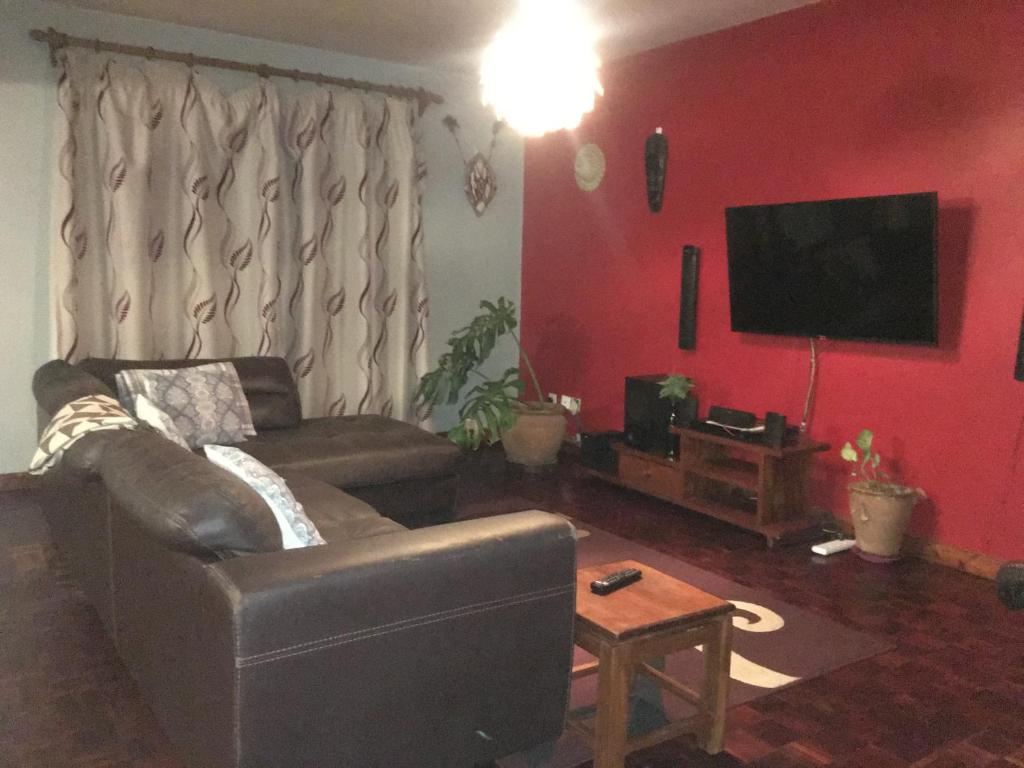 salon z kanapą i telewizorem z płaskim ekranem w obiekcie Private room in Townhouse, Kilimani. w mieście Nairobi