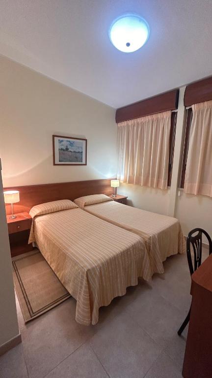 a bedroom with two beds and a table and two lamps at Il Nocchiero City Hotel in Soverato Marina