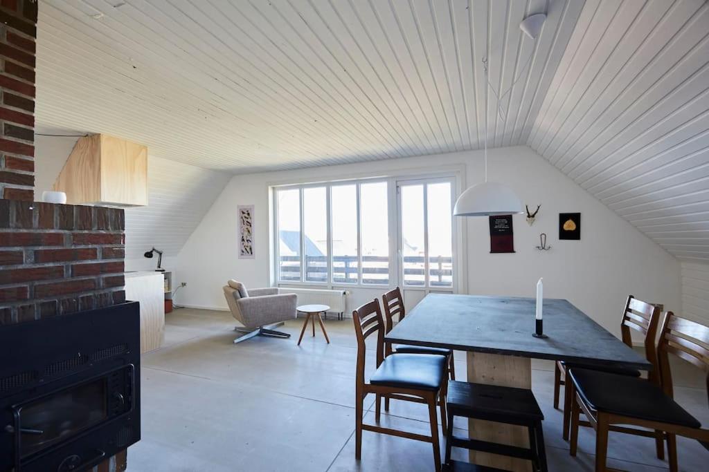 Apartment with a unique view في Vestervig: غرفة معيشة مع طاولة طعام وكراسي