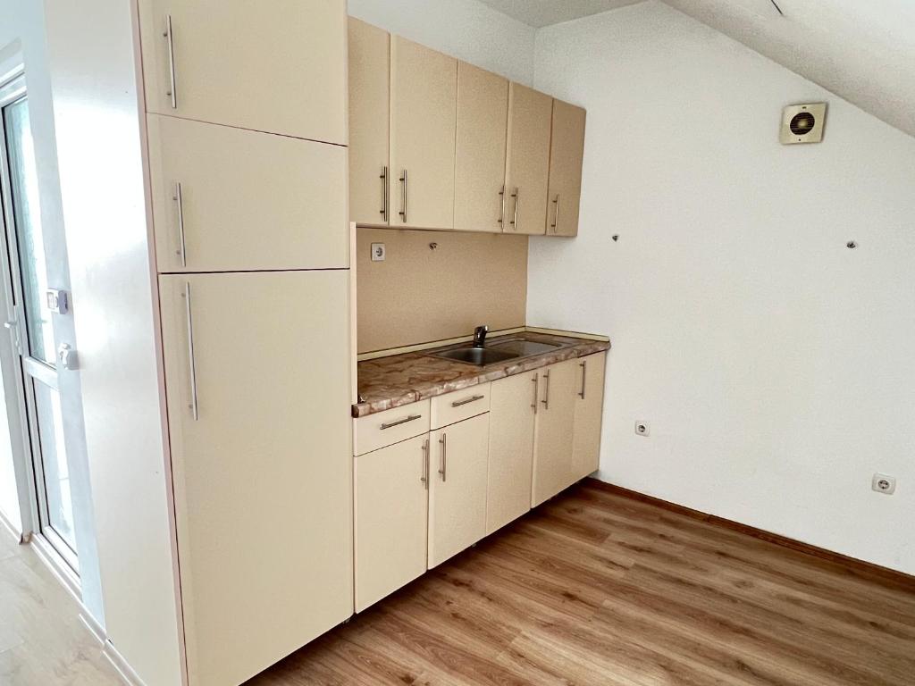 uma cozinha vazia com armários brancos e um lavatório em Vila Andrra em Struga