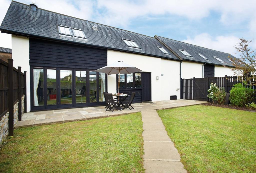 a white house with a table and an umbrella at Hunters Moon in Honiton