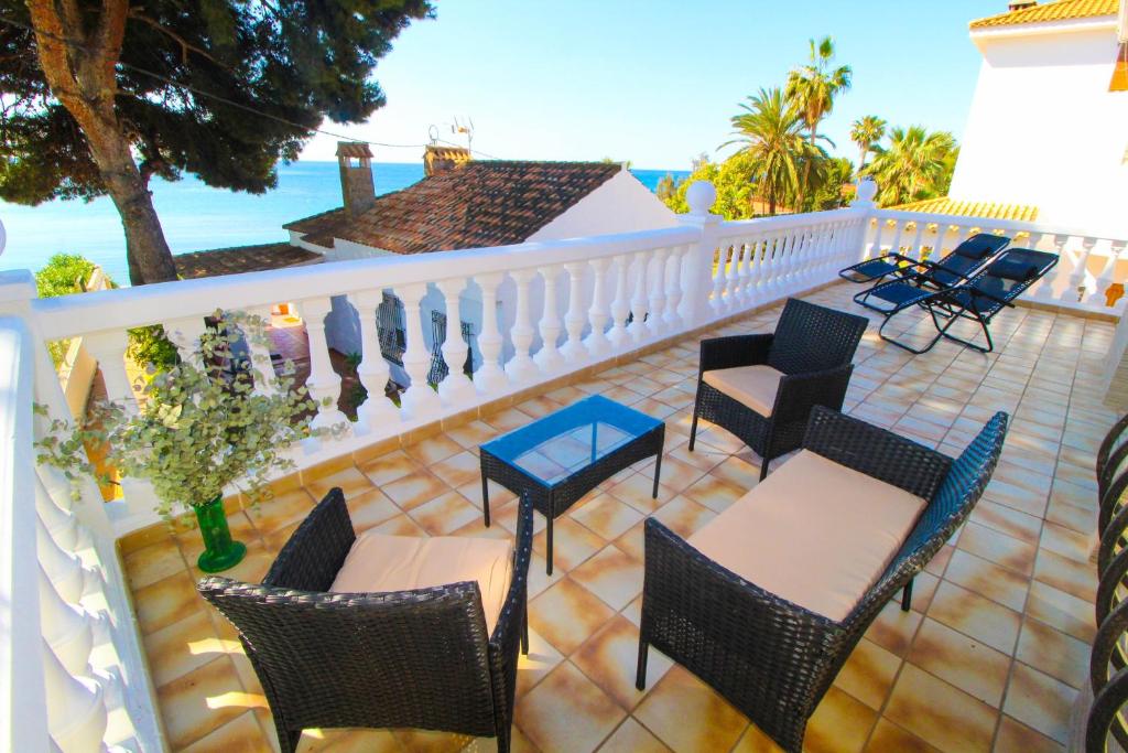 a balcony with chairs and tables and the ocean at Great villa, Sea views, 20 secs walk to the beach, BBQ, 9 people, 5 mins car from Alicante city center, sailing club 3 mins walk in Alicante