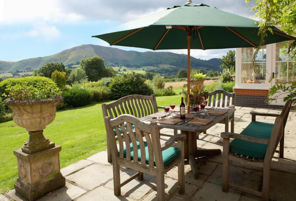 a table with a green umbrella on a patio at The Oaks in All Stretton