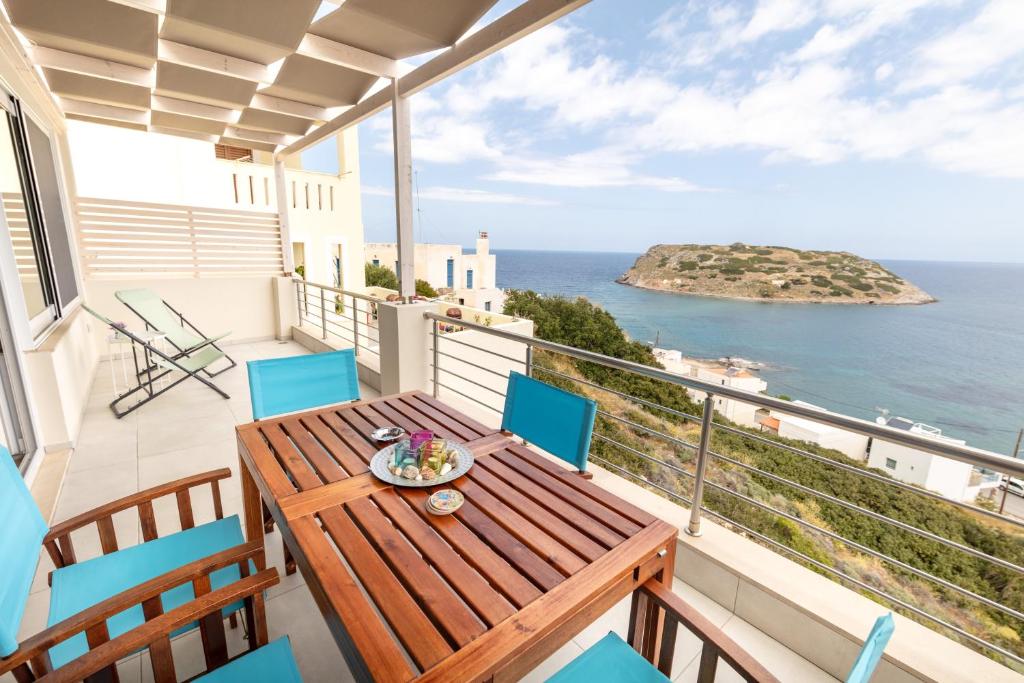 einen Balkon mit einem Holztisch, Stühlen und Meerblick in der Unterkunft Serenity apartment Mochlos in Mochlos