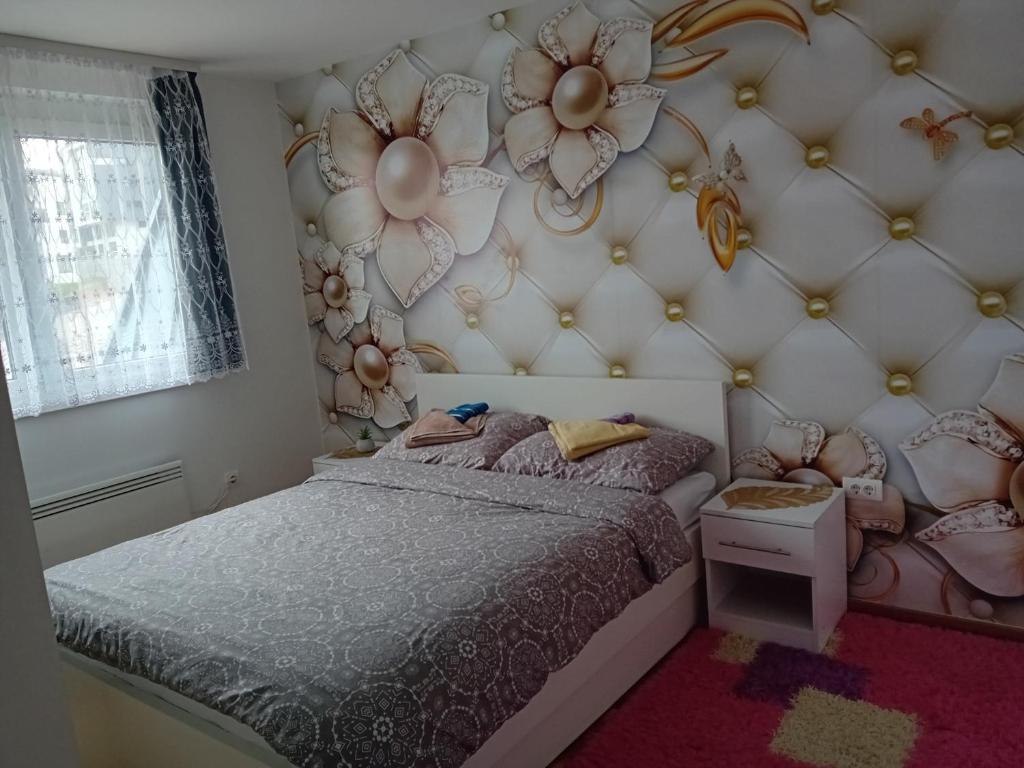 a bedroom with a bed and a flower wall at Apartman "AROMA 1"Bjelasnica in Bjelašnica