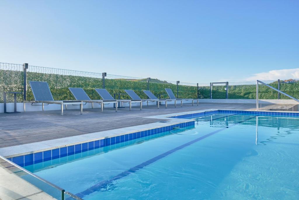 a swimming pool with lounge chairs on a roof at Zimbali Lakes Boulevard Suites in Ballito