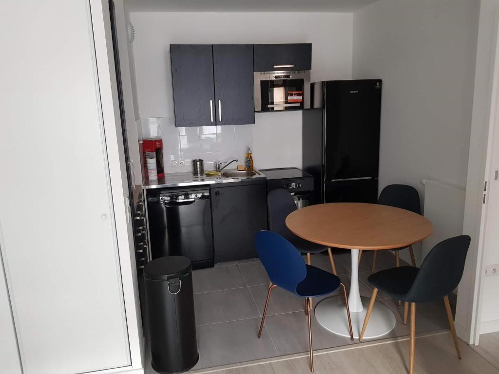 a small kitchen with a wooden table and blue chairs at Appart neuf entre Paris et Versailles, A 5 mn école Ducasse in Meudon