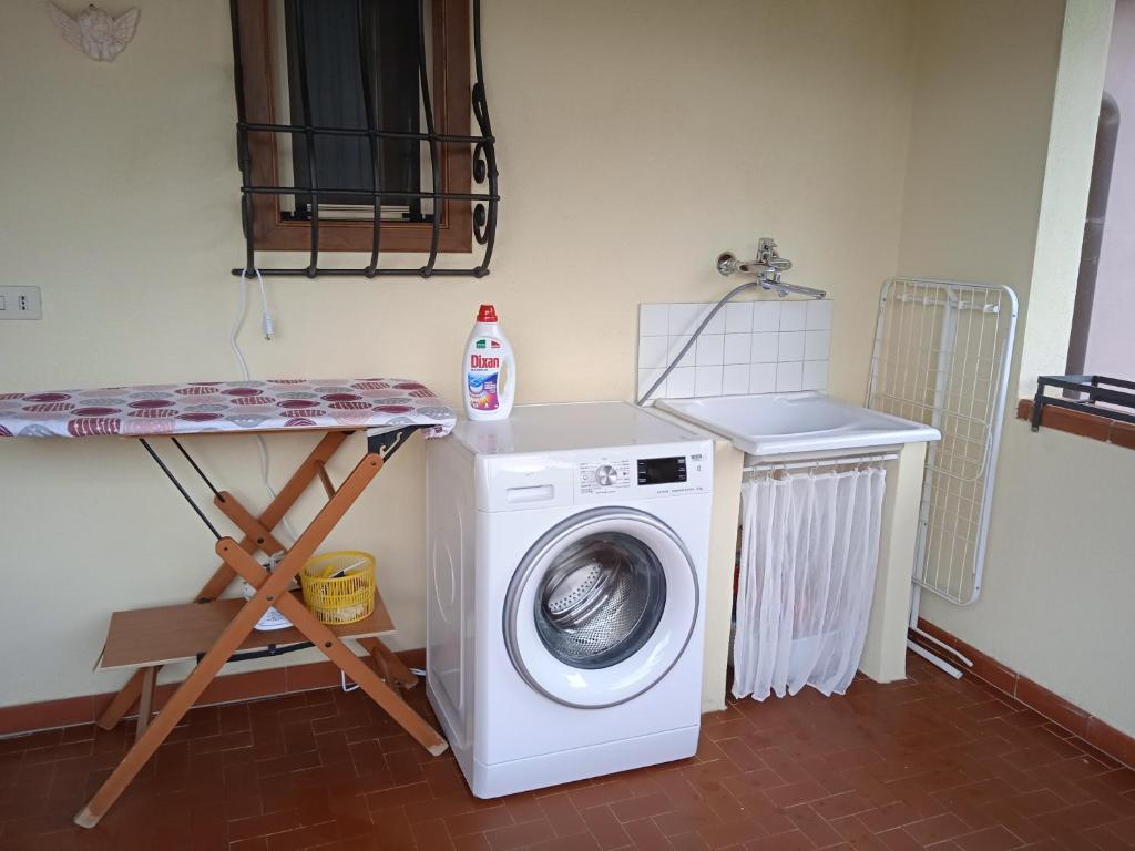 uma lavandaria com uma máquina de lavar roupa e uma prateleira em Rustico degli Ulivi em Vallecchia