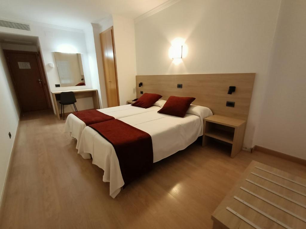 a bedroom with a large white bed with red pillows at Hotel Vilobi in Vilobí d'Onyar