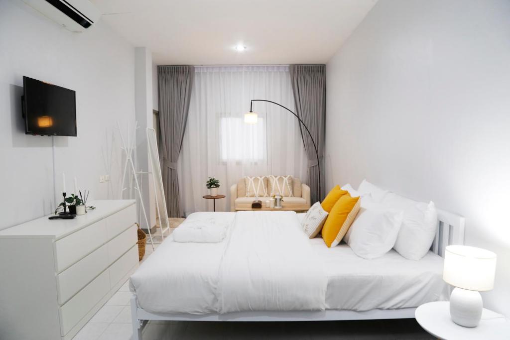 a white bedroom with a large white bed with yellow pillows at Kanda Boutique in Patong Beach