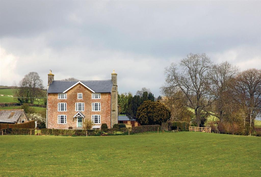 une grande maison en briques avec une grande pelouse dans l'établissement Upper Mowley, à Kington