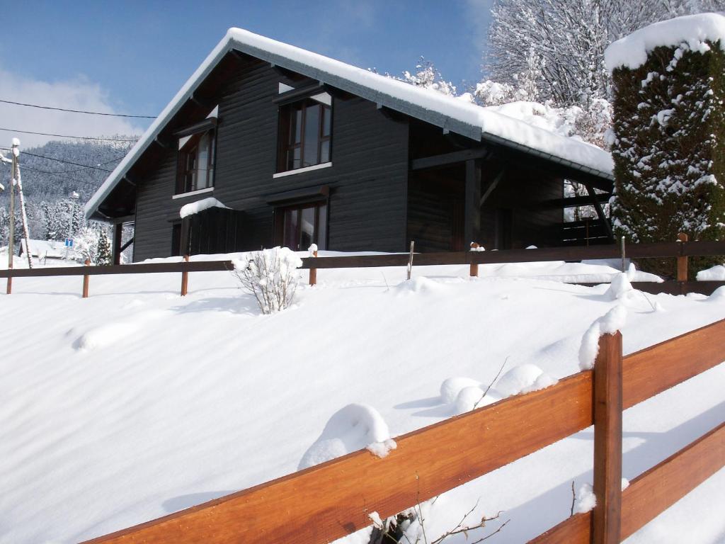 uma casa coberta de neve com uma cerca de madeira em Les Chalets Du Pres D'amont em Vagney