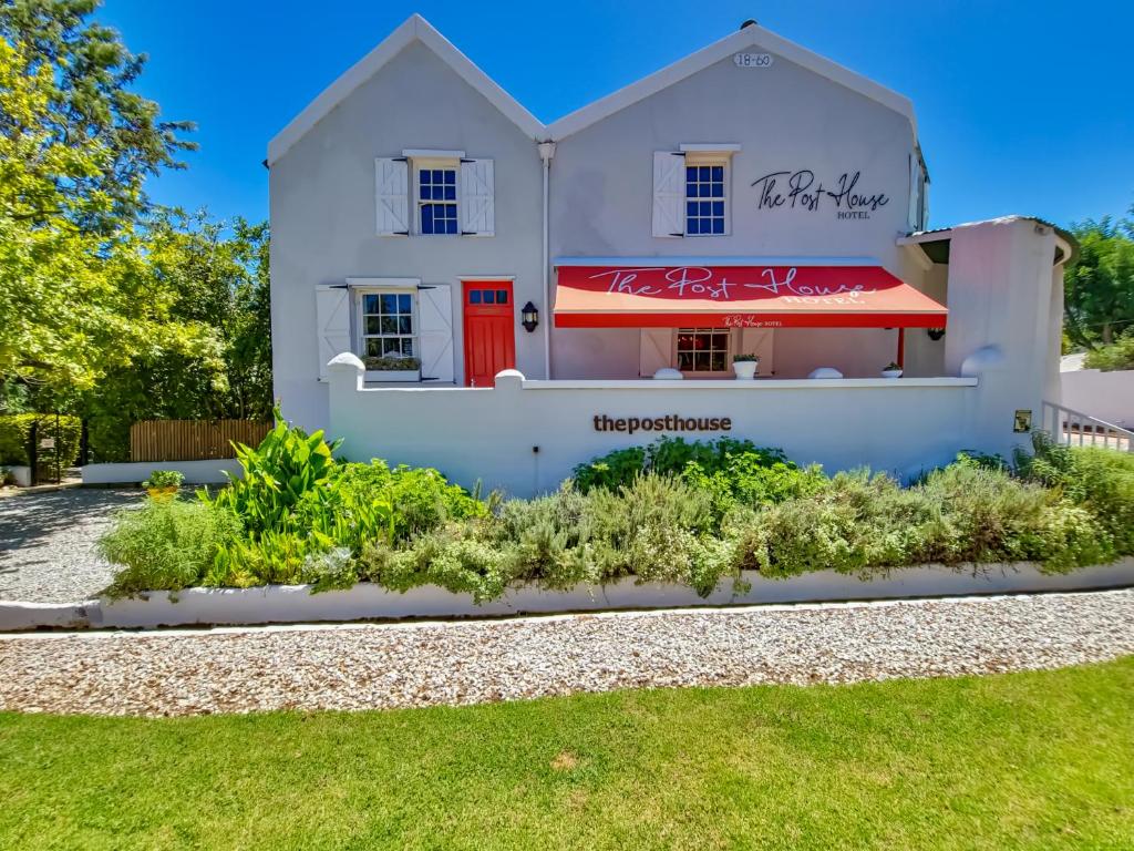 a white house with a red door at The Post House Hotel - no children under the age of 16yrs in Greyton