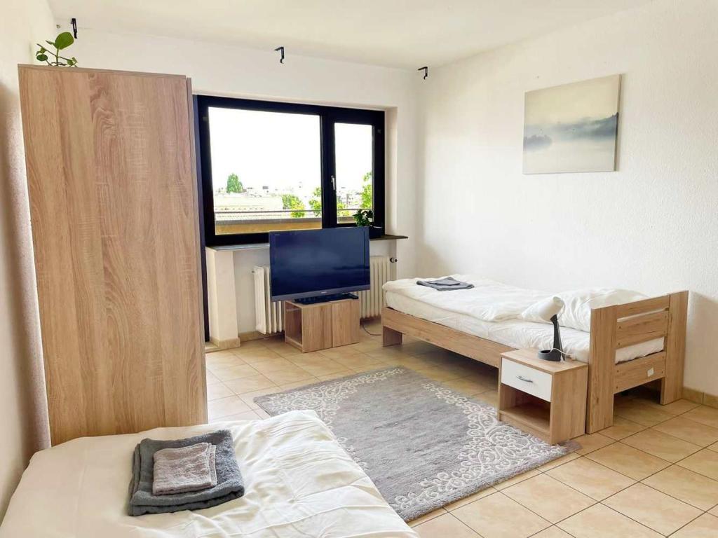 1 dormitorio con 2 camas y TV. en Schickes Apartment in Offenbach am Main en Im Teller