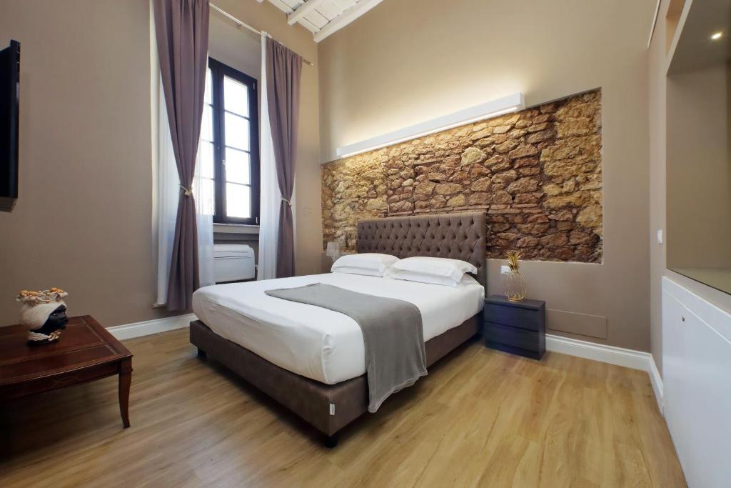 a bedroom with a bed and a stone wall at Il Borgo Your Luxury Suites in Nettuno