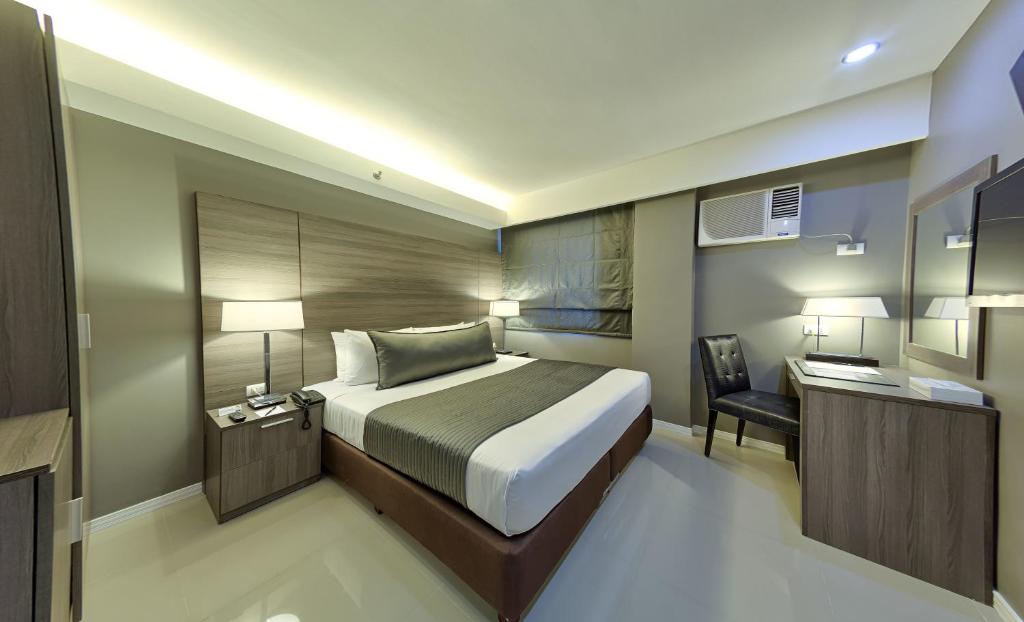 a bedroom with a bed and a desk and a chair at Astoria Greenbelt in Manila