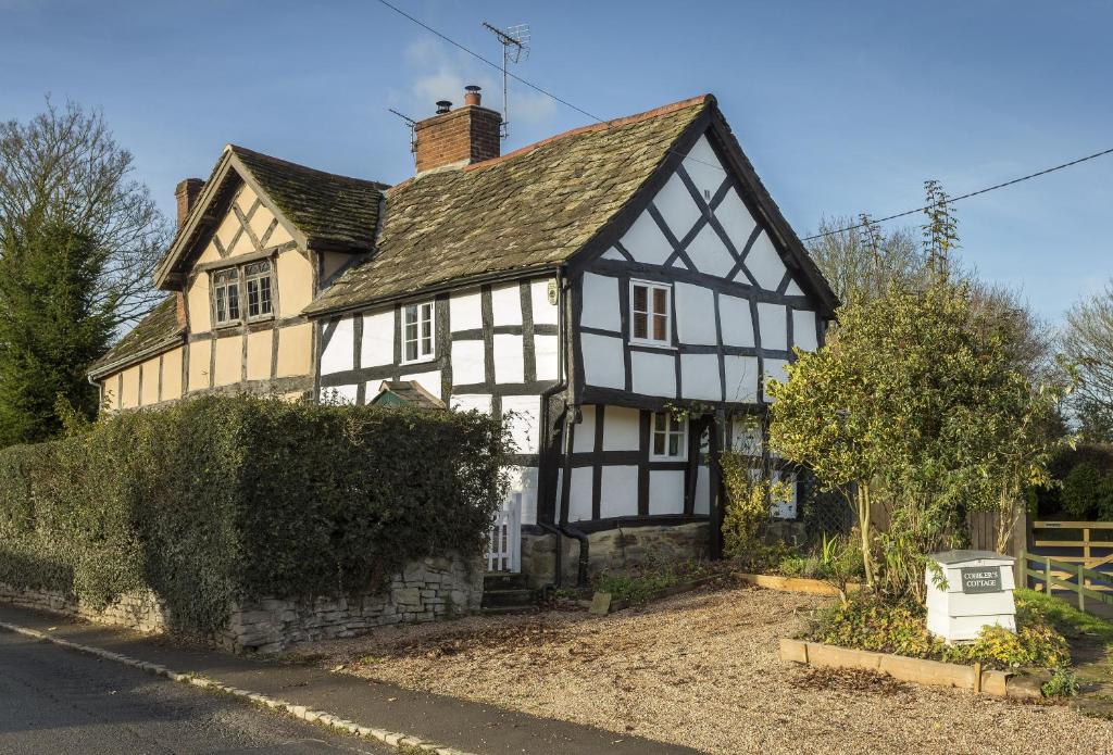 an old black and white house on a street at Cobbler's Cottage in Pembridge