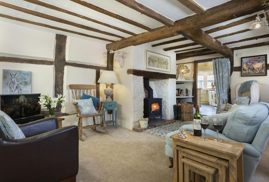 a living room with a fireplace and blue chairs at Cobbler's Cottage in Pembridge