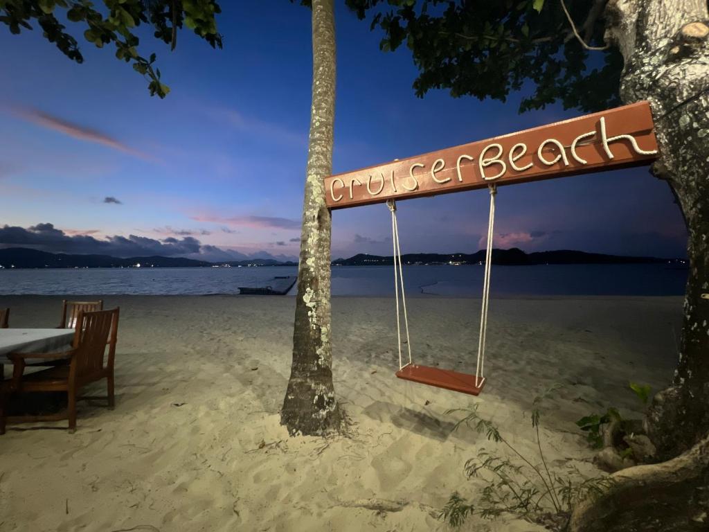 a sign on a beach with a table and a tree at Cruiser Island By Swiss-Belhotel in Ko Lone