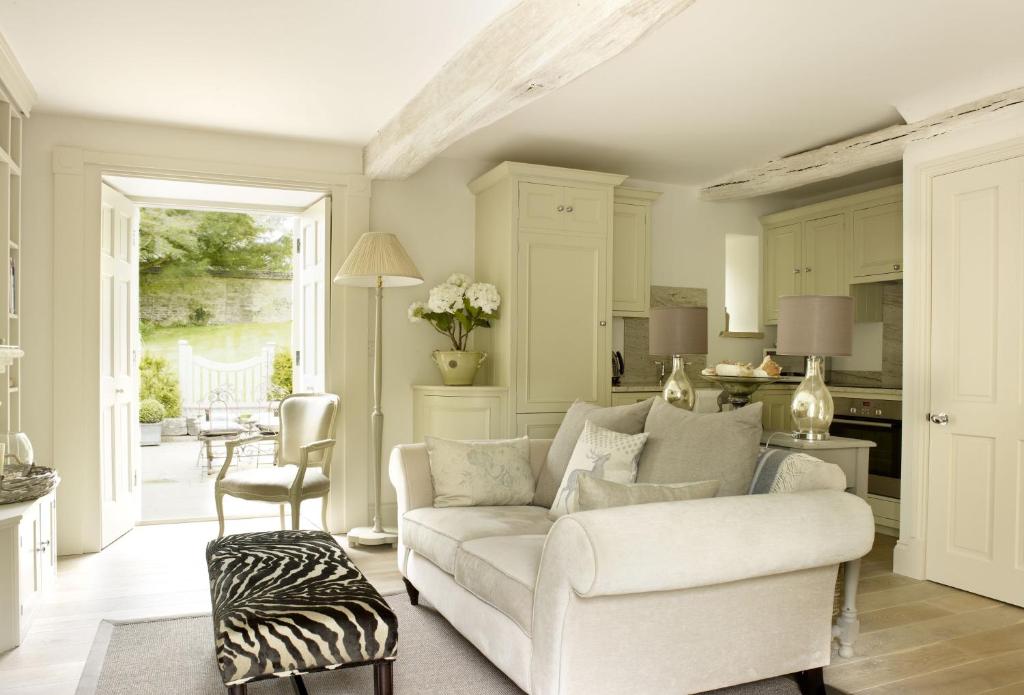 a living room with a white couch and a kitchen at Rectory Cottage in Stamford